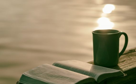 green ceramic mug beside book